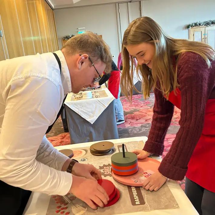 Hands-on team training activity with colleagues assembling cake components during The Cake Factory experiential learning workshop in Ireland