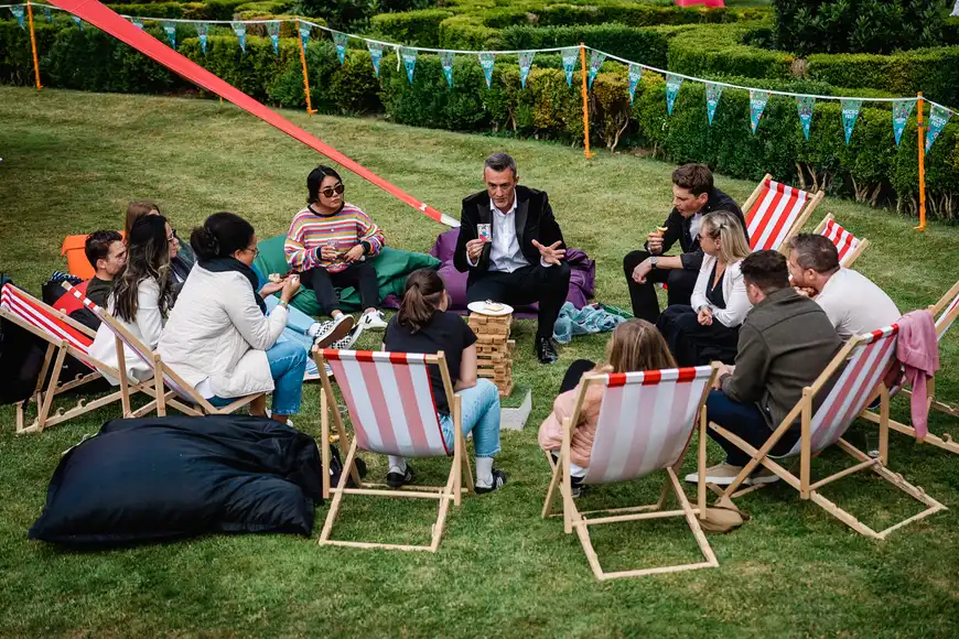 Team sitting on deckchairs listening to a magician entertaining during a relaxed corporate summer event