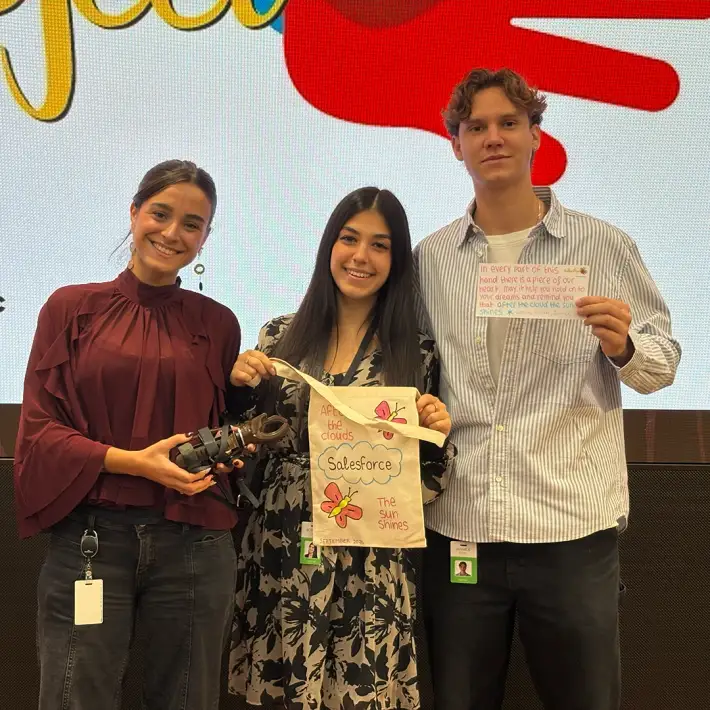 Team members at The Hand Project CSR activity in Ireland presenting a prosthetic hand, decorated donation bag, and handwritten note for the recipient.