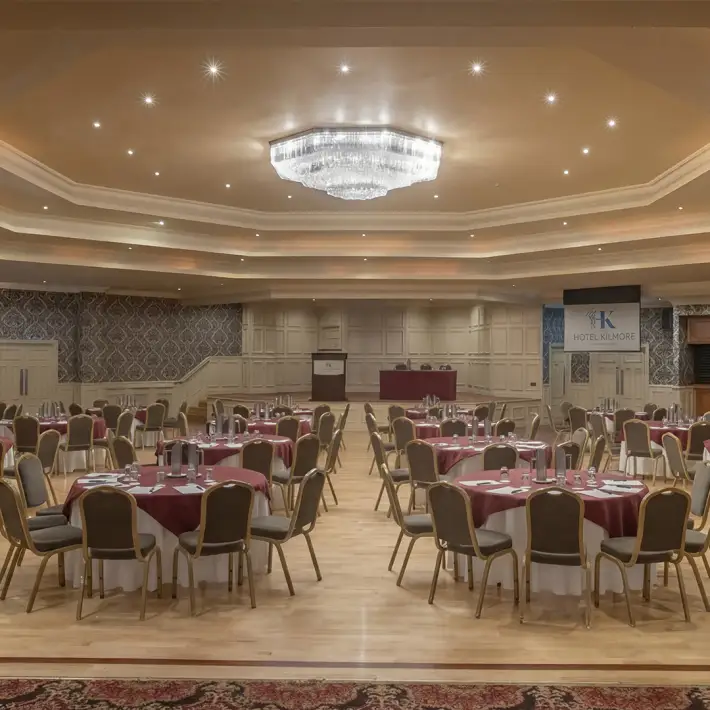 Large corporate event space with round table seating and stage at Hotel Kilmore in Cavan