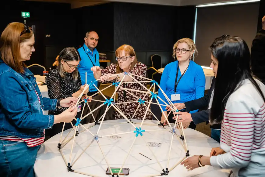 People collaborating to build domeworks structure during a team training activity.