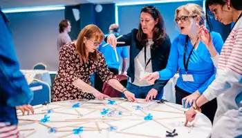 Senior leadership team participating in a hands-on team development activity during a leadership retreat in Ireland, focused on collaboration and problem-solving.