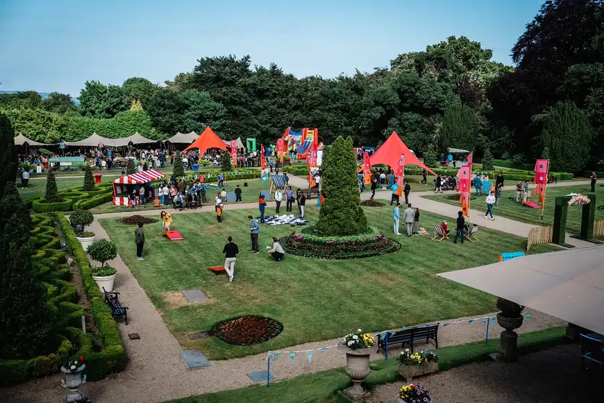 Aerial view of large summer corporate festival with tents, inflatables, food stalls, and team building games