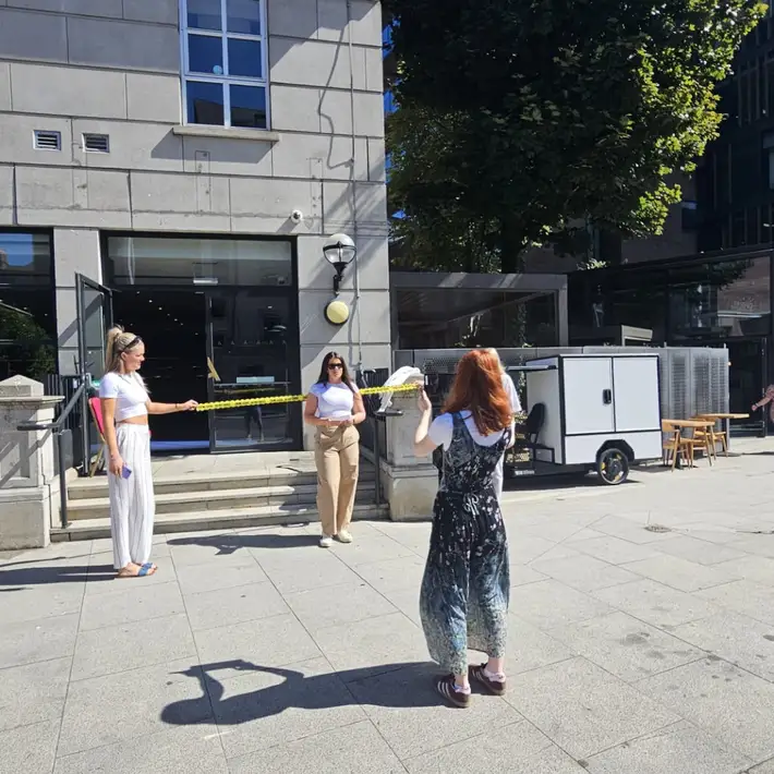 Corporate team building participants filming a mock crime scene outside a venue during the Manor House Murder event in Dublin, using props and caution tape for an interactive murder mystery activity.