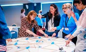 Senior leadership team participating in a hands-on team development activity during a leadership retreat in Ireland, focused on collaboration and problem-solving.