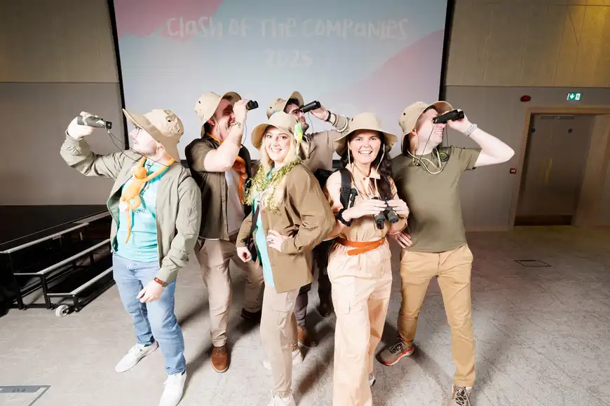 Team dressed up as explorers posing for a picture by looking through their binoculars. | County Kerry