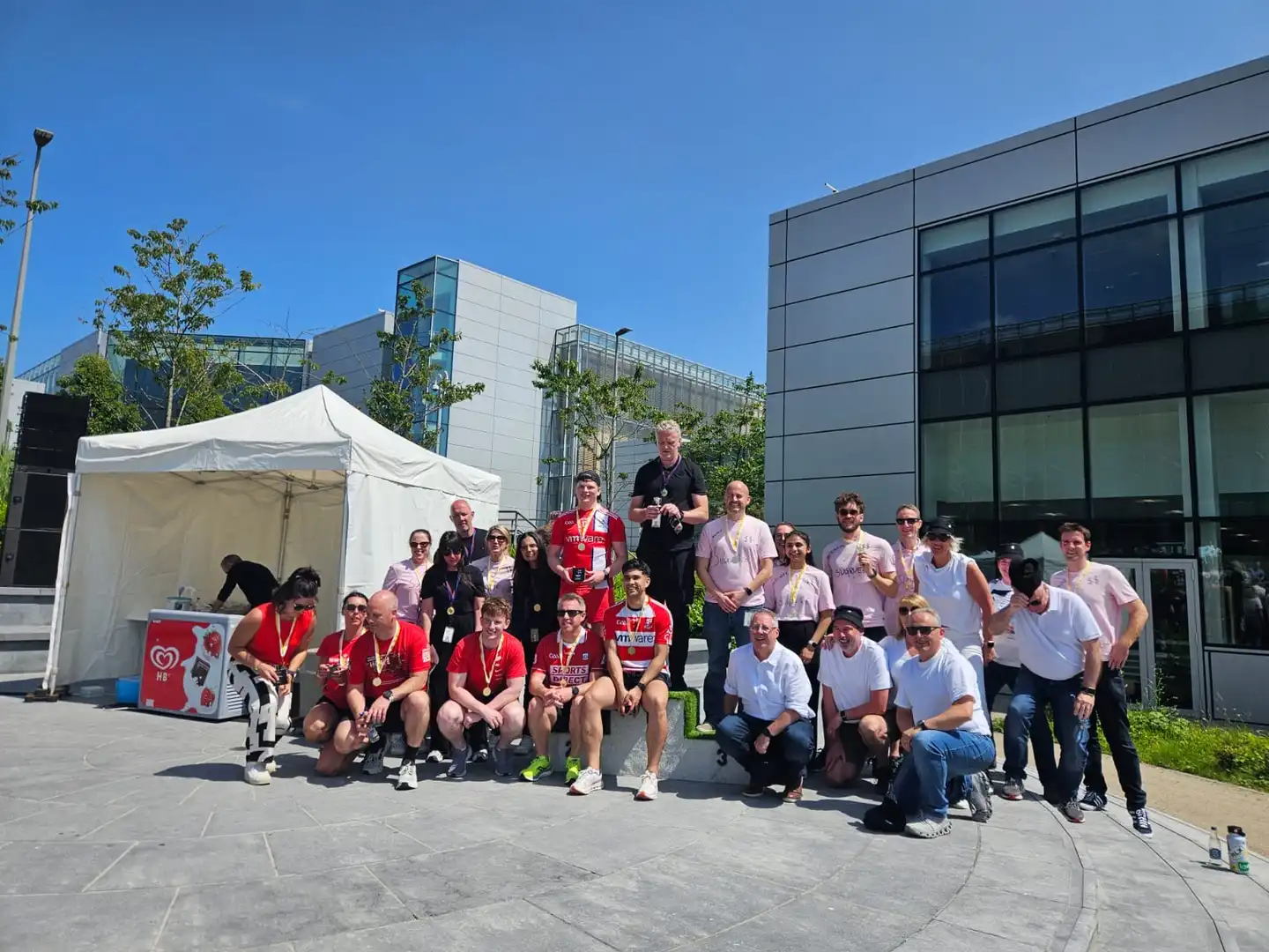 Winners on podium holding medals and sweets at Apple’s summer sports day