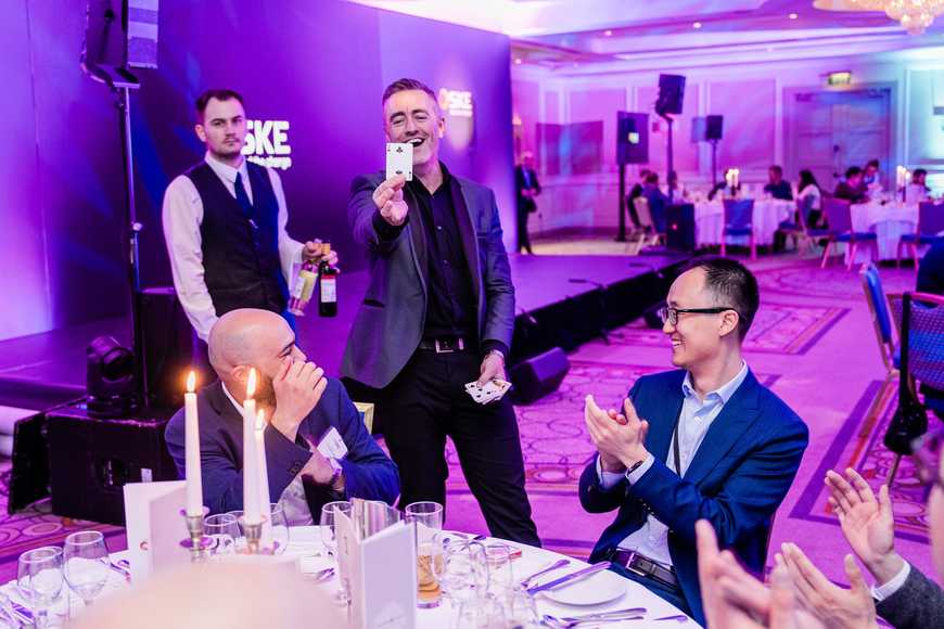 Corporate magician performing a live card trick at a Christmas team building dinner event in Ireland.