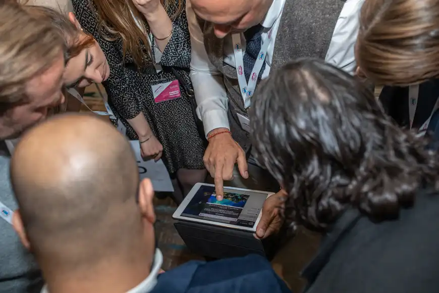 Team crowding around an iPad to solve a question during interactive digital quiz challenge