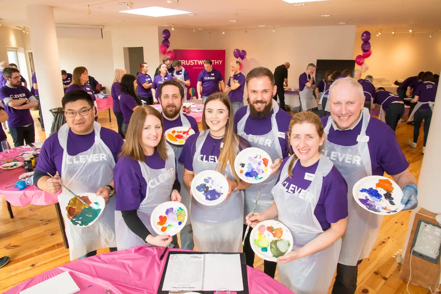 Corporate team smiling while holding painted plates during a collaborative team building activity called The Big Picture