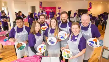 Corporate team smiling while holding painted plates during a collaborative team building activity called The Big Picture in Ireland