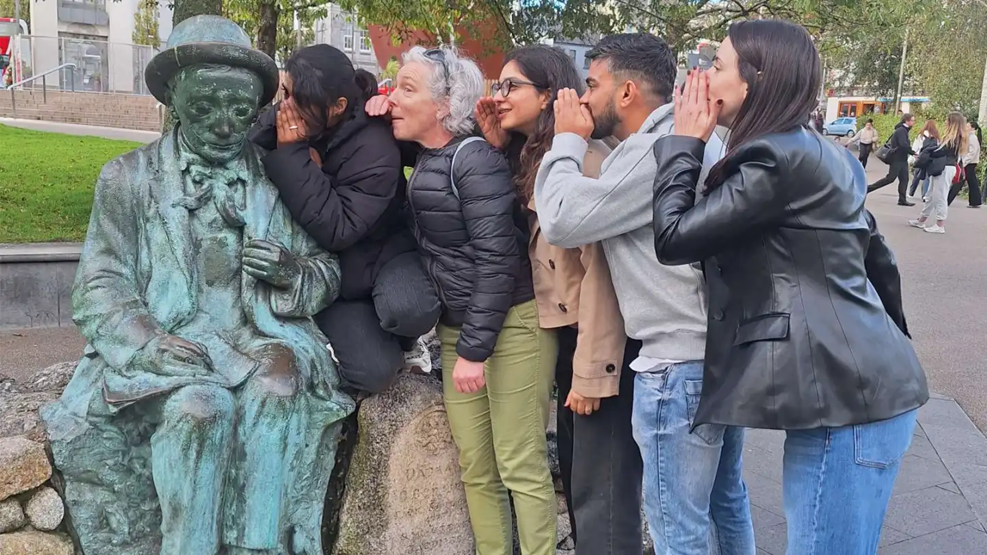Fidelity Investments employees taking part in a Galway City digital treasure hunt, posing beside a statue during their team-building activity.