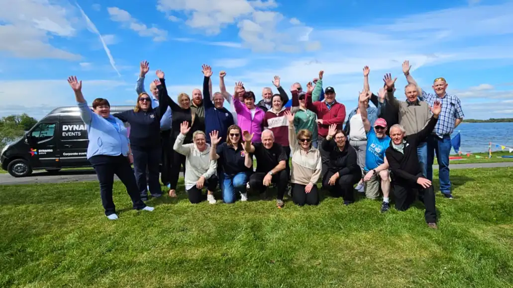 Large public sector group taking part in outdoor team building activities in Ireland, celebrating together by a lake.