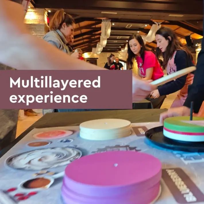 Hands assembling cake elements with tools and materials, illustrating teamwork and coordination.