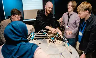 Facilitator leading a corporate team development session, smiling and engaging with participants at a workshop, wearing a Dynamic Events shirt.
