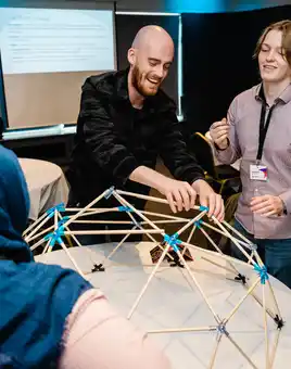 Facilitator leading a corporate team development session, smiling and engaging with participants at a workshop, wearing a Dynamic Events shirt.