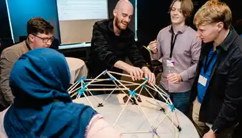 Facilitator leading a corporate team development session, smiling and engaging with participants at a workshop, wearing a Dynamic Events shirt.