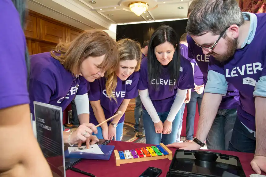 Corporate team building workshop in Ireland with Code Breaker problem solving game, Energia team collaborating indoors.