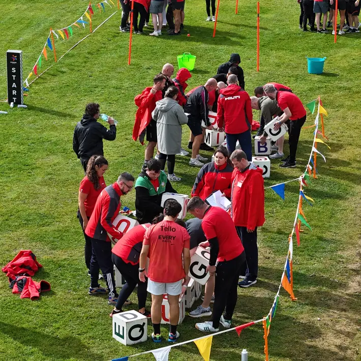 Hilti employees working together in a Team Olympics challenge with giant alphabet blocks during summer party team building