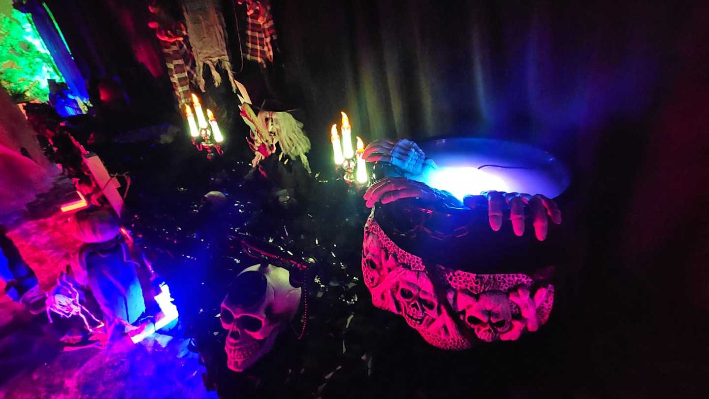 A cauldron made of bones on a creepy table that has uplights in blue and red colours