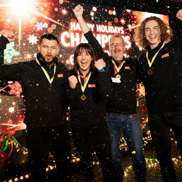 Corporate team celebrating after winning a Christmas digital treasure hunt in Ireland, wearing medals with festive decorations and confetti.