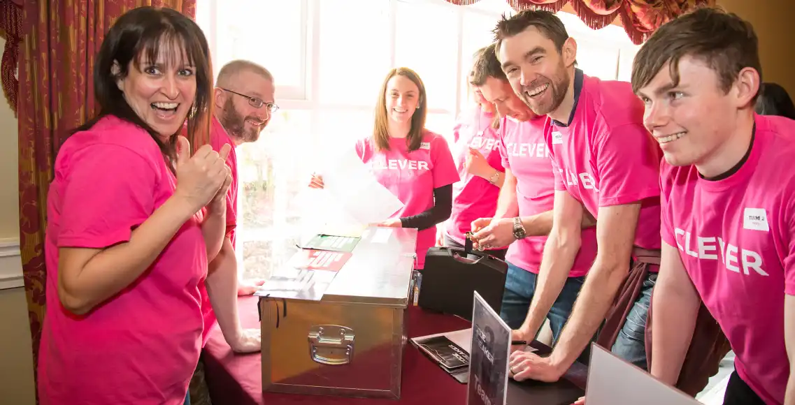 Corporate team enjoying escape room team building challenge in Ireland, smiling and solving puzzles together.