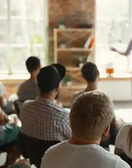 Corporate team training workshop during a company kick off meeting in Ireland, with employees listening to a facilitator presenting business goals.