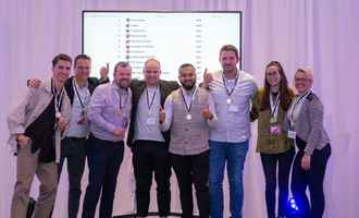 Corporate quiz winners posing with medals in front of live team scoreboard during team building event in Ireland