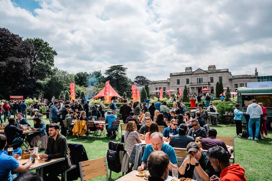 Colleagues enjoying food and drinks together at picnic tables during a summer team building event