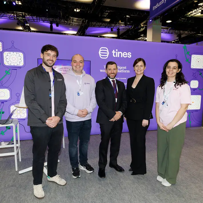 Five representatives posing in front of the purple Tines cybersecurity automation exhibition stand at the NCSC Cyber Expo.