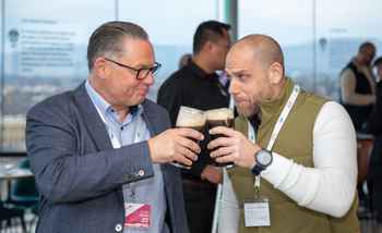 two professionals toasting with pints of Guinness, smiling and engaged in conversation
