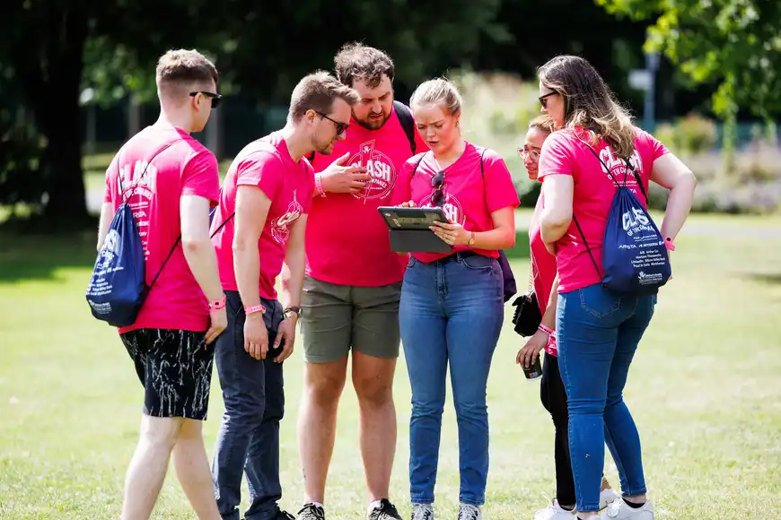 Corporate treasure hunt team building activity in Ireland, group solving outdoor challenge with tablet during event.