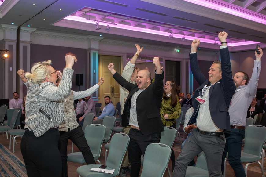 Excited corporate team cheering after quiz victory at indoor team building event in Ireland