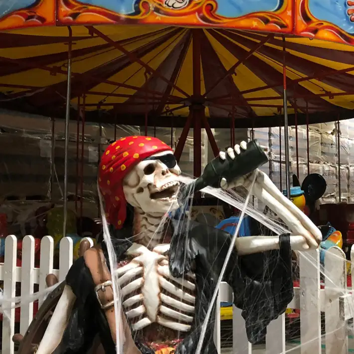 Skeleton pirate Halloween decoration at corporate family fun day with carnival rides and themed entertainment.